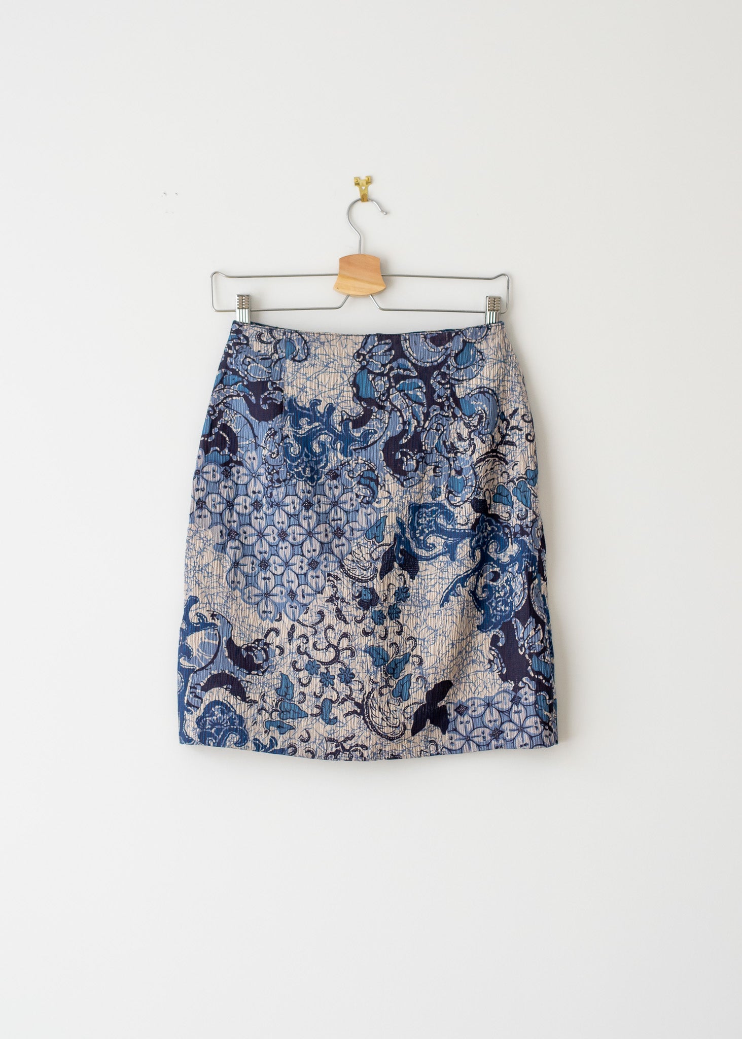 knee-length blue floral pattern vintage pencil skirt on a hanger against a white background