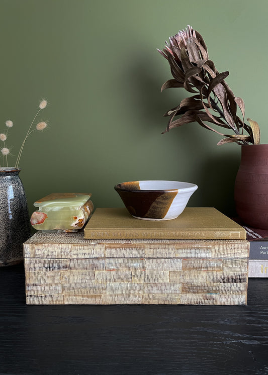 Decorative vintage shell box with a vintage ceramic bowl on top against a green wall